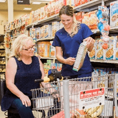 Home Care Assistant Shopping With Elderly Woman at Grocery Store